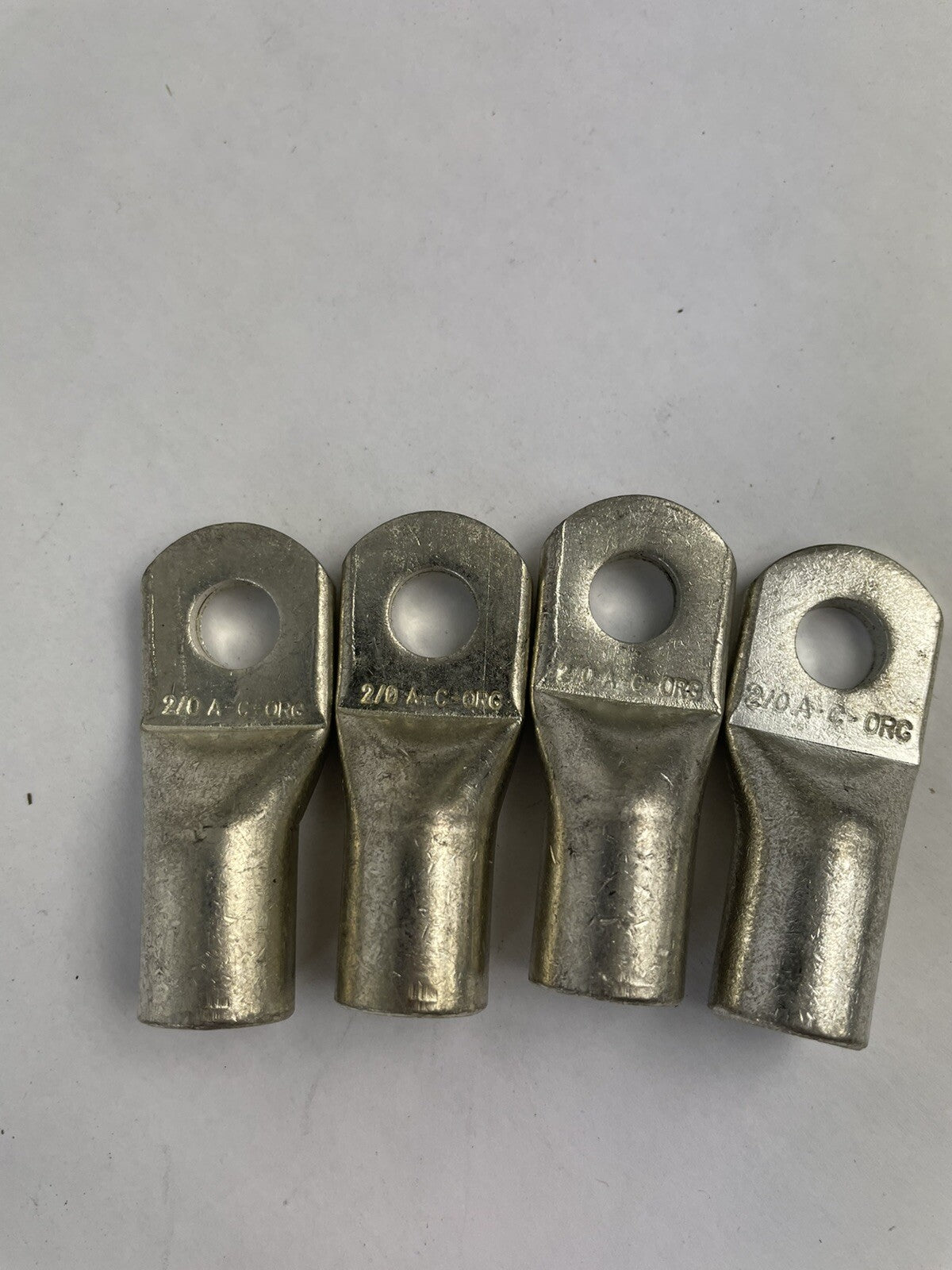 Lot of 4 heavy-duty 2/0 AWG copper battery cable ring terminal lug connectors for automotive, marine, RV, and industrial electrical applications.