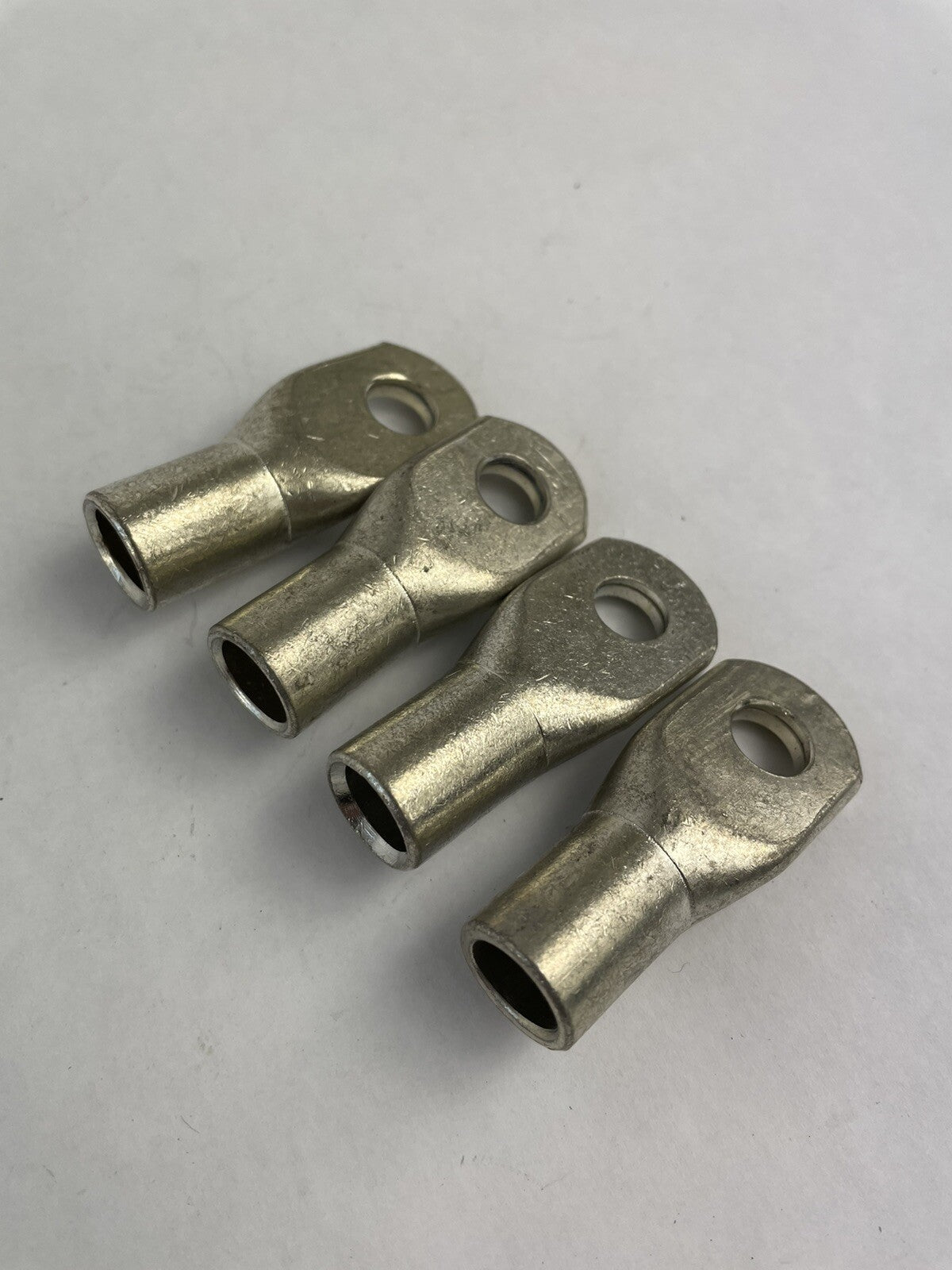 Lot of 4 heavy-duty 2/0 AWG copper battery cable ring terminal lug connectors for automotive, marine, RV, and industrial electrical applications.