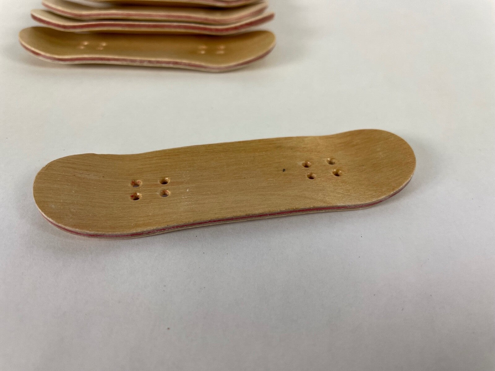Lot of 10 wooden fingerboard mini skateboards with natural wood grain finish for fingerboarding, crafts, and customization.